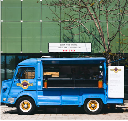 A bright blue Silly Yaks food truck with the side open ready to serve. The back of the truck displays a menu.