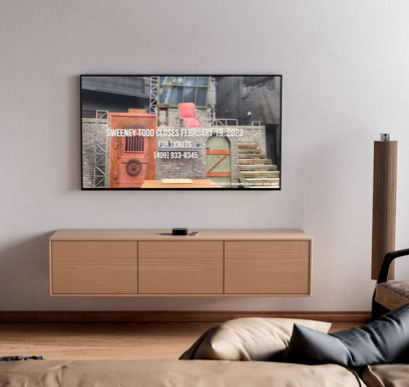 A living room scene with a wooden, floating entertainment center and a tv mounted above showing a work sample from a promotional video created by Jenna Crump